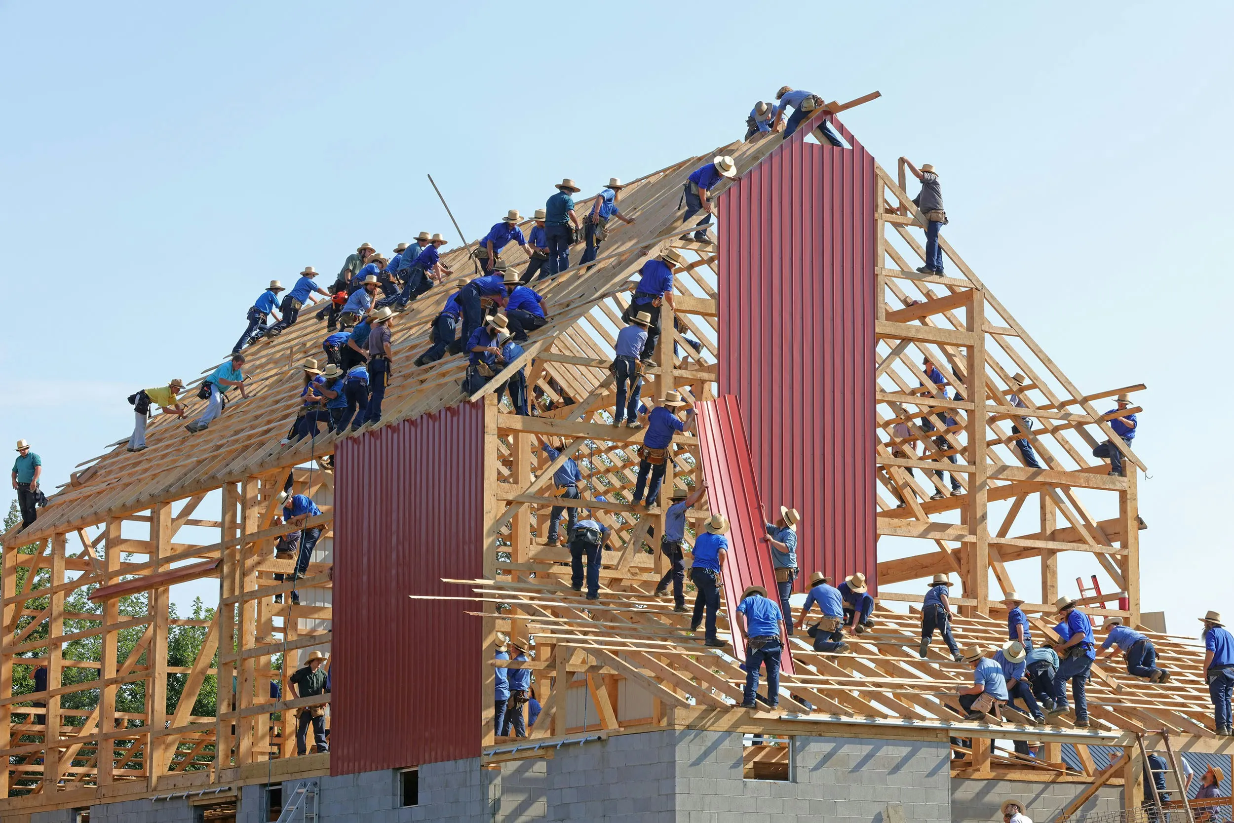 Viele Menschen bauen gemeinsam ein Haus – Sinnbild für gemeinsamen Unternehmensaufbau und Mitarbeiterbeteiligung